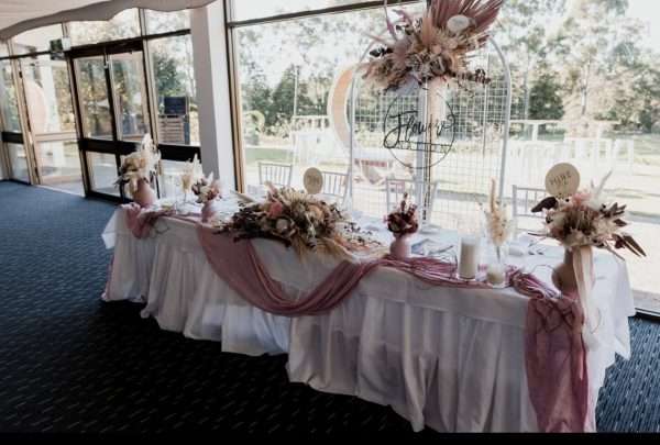 romantic pink bridal table flowers. wedding reception floral backdrop. wedding reception bridal table setup. pink cheesecloth wedding table draping.