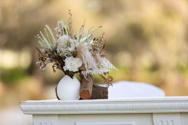 small dried and preserved hire flower posy, with rustic log element in white vase. neutral tones. lux glamour range